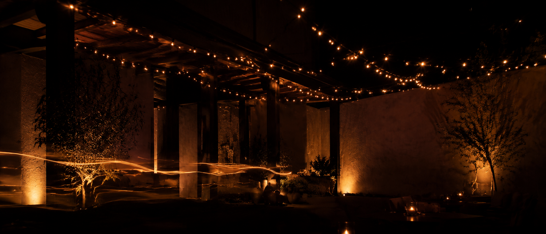 Fictional night dining terrace with warm string lights and abstract light trails